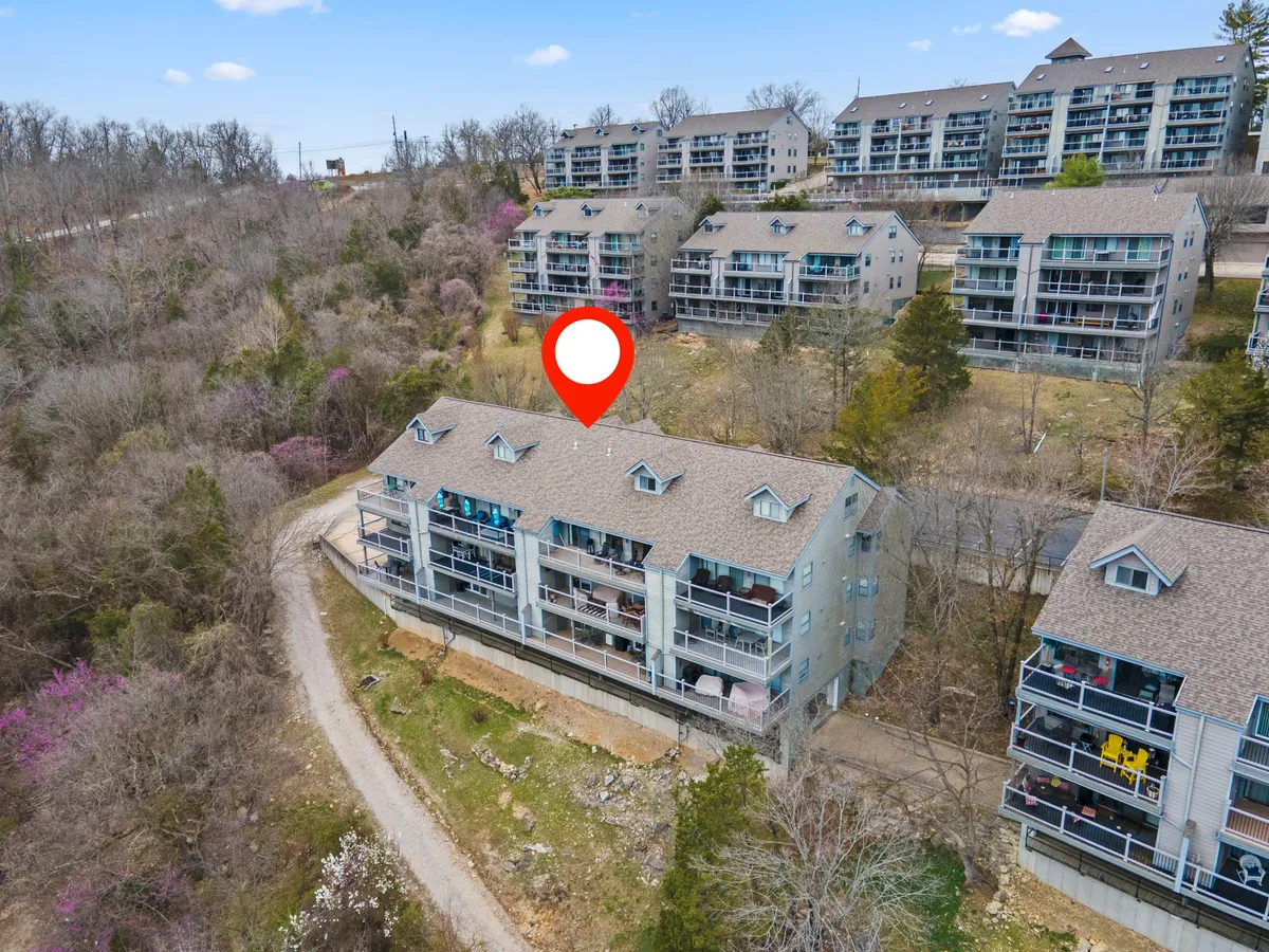 A welcoming view of a multi-unit residential building set among natural landscape, with a road leading up to the property. Private balconies invite morning coffee or sunset relaxation, while the surrounding greenery hints at both community and seclusion.