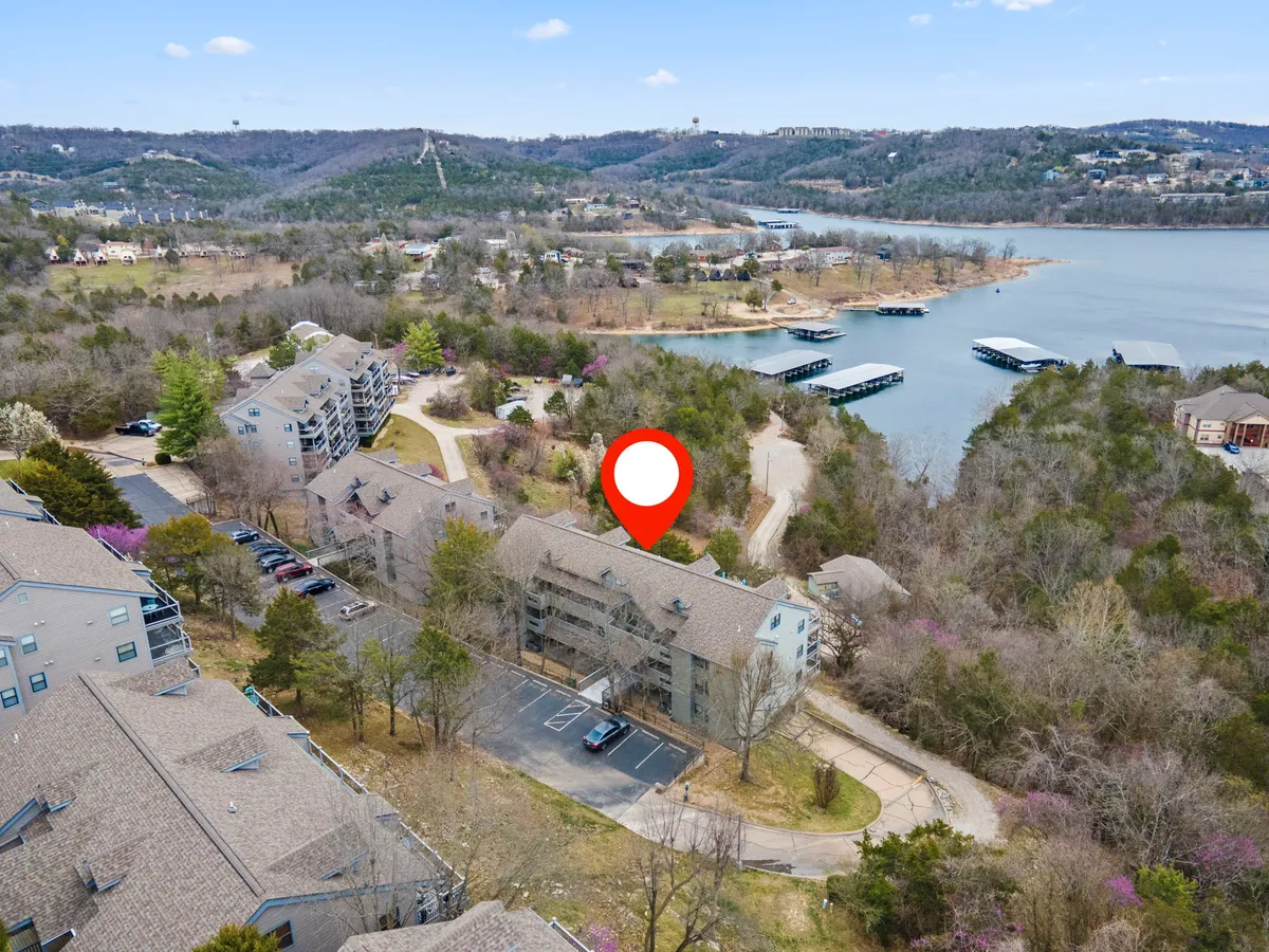 A serene lakeside scene featuring the lake, marinas, surrounding hills, and residential buildings. The image hints at water sport activities, wildlife, and a laid-back, scenic environment ideal for exploration and recreation.