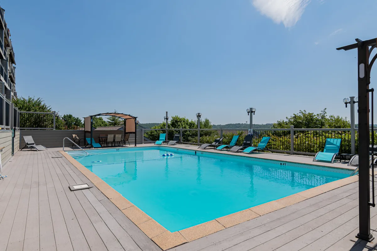 An inviting outdoor swimming pool area with lounge chairs, a canopy for shade, and lush surrounding greenery. The tranquil setting invites both relaxation and family fun, beautifully complementing lake days.