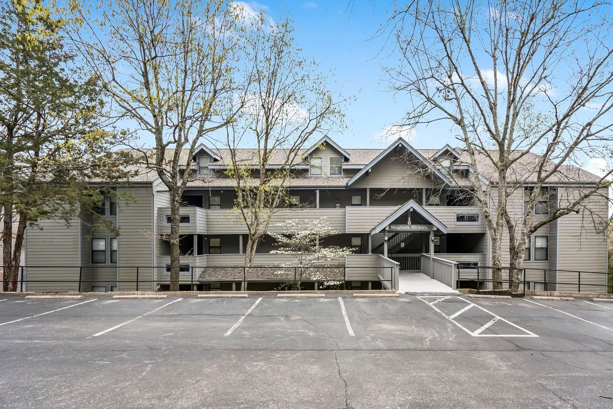 The facade of a residential building surrounded by trees and a clearly visible parking area, offering a sense of community and well-organized shared spaces.