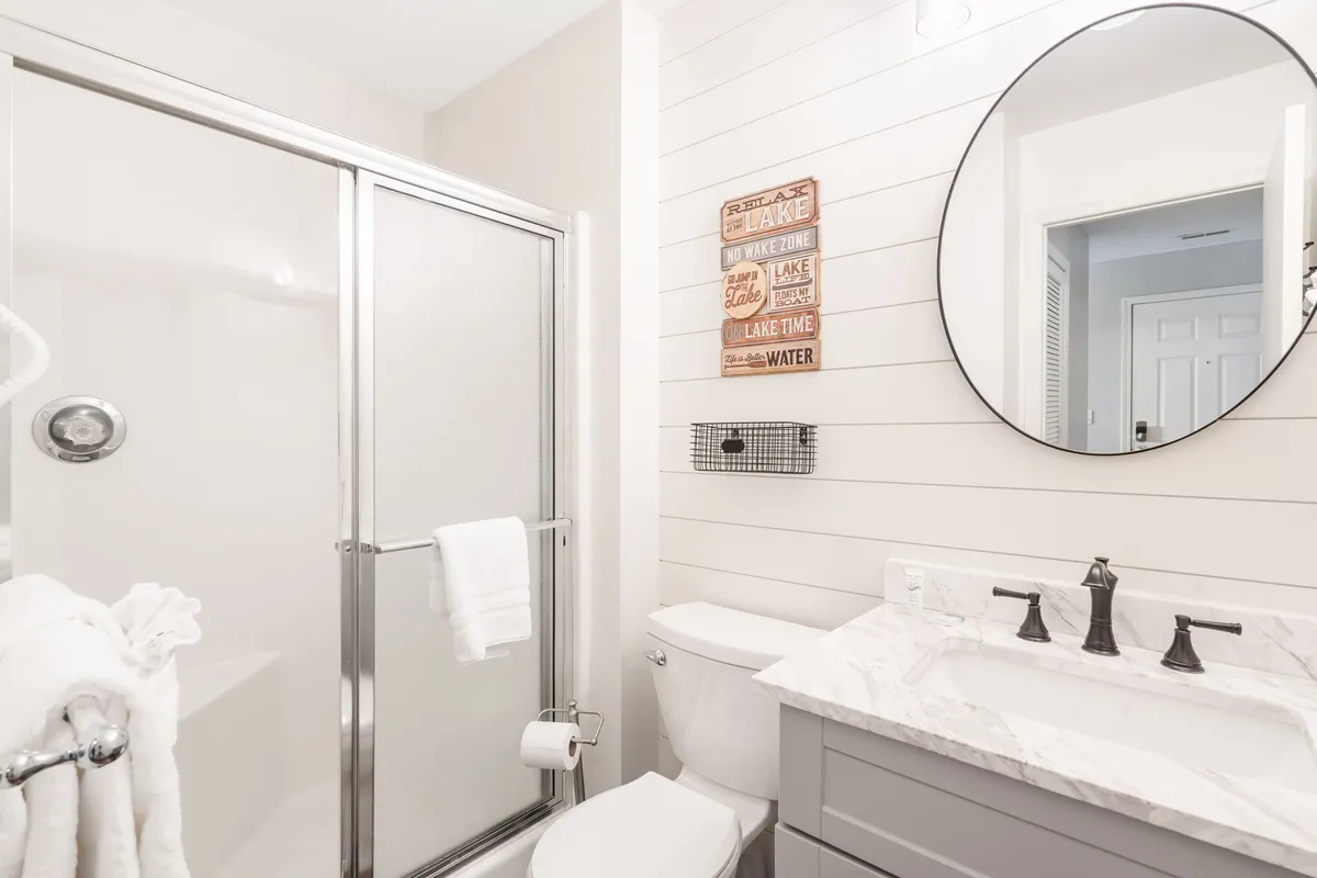 A modern bathroom with a shower area, vanity featuring a marble countertop, and decorative accents. Morning light fills the space, highlighting the inviting atmosphere for personal care routines.